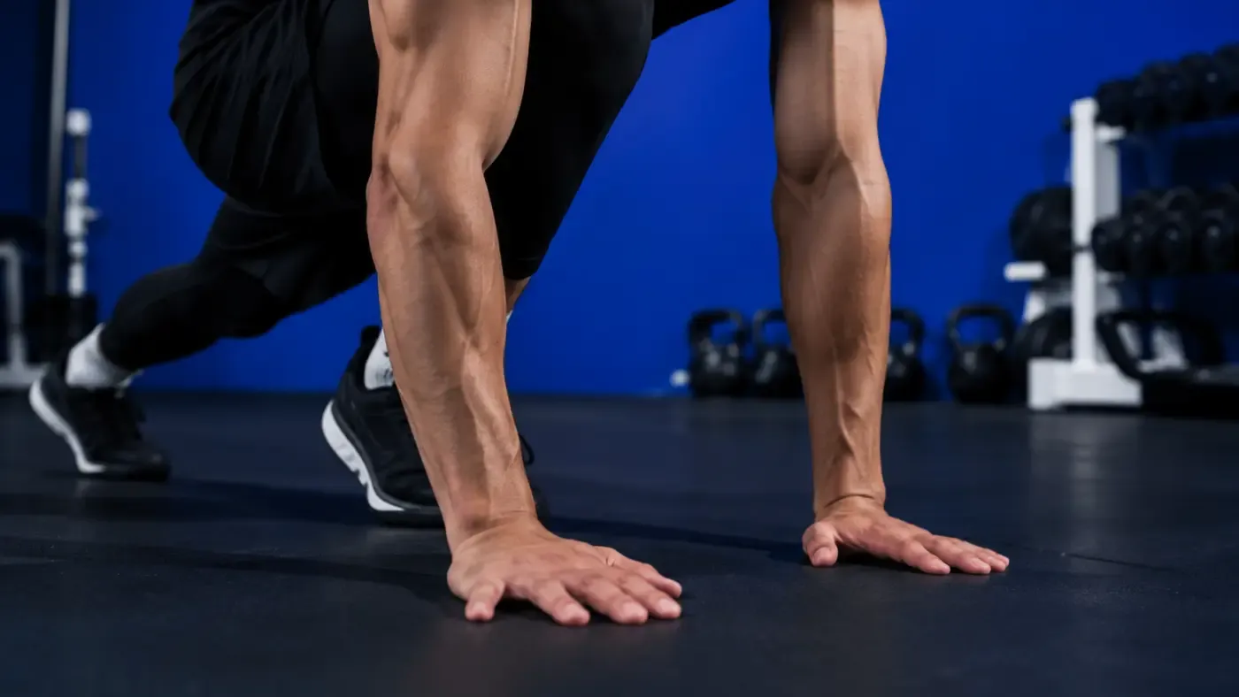 Étirement dynamique en fente dans un studio de sport au mur bleu profond, équipement flou en arrière-plan, ambiance premium